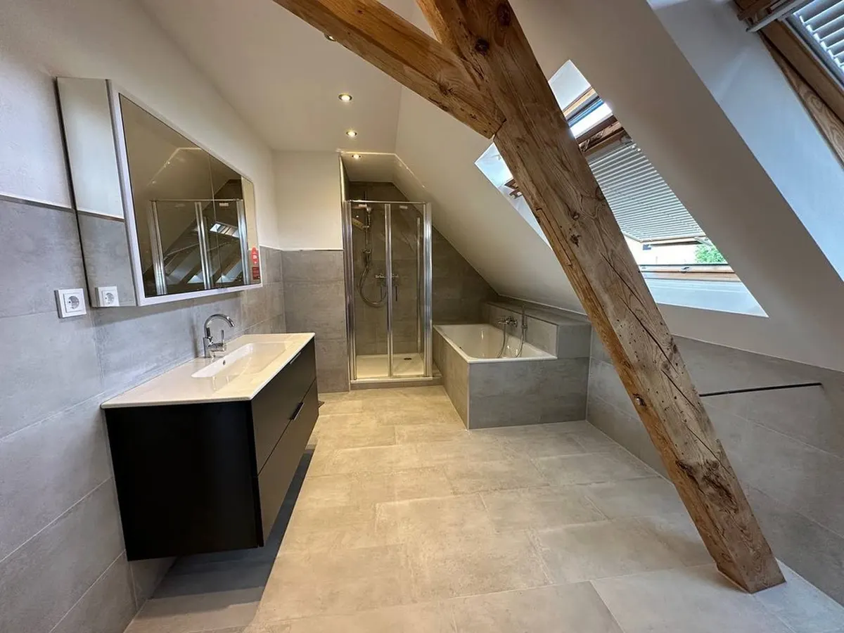 Fertiges Dachgeschoss-Bad mit Dusche, Badewanne und Waschtisch unter der Dachschräge